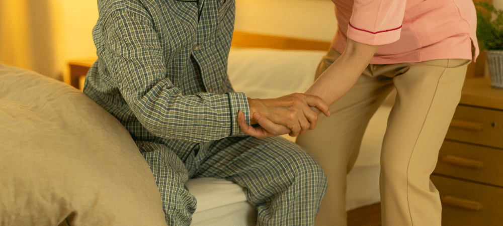 carer helping patient out of bed